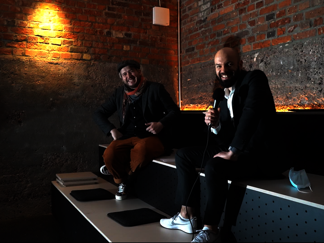 Ein Concordia Mitarbeiter mit einem Mikrofon in der Hand und ein Gast sitzen nebeneinander.