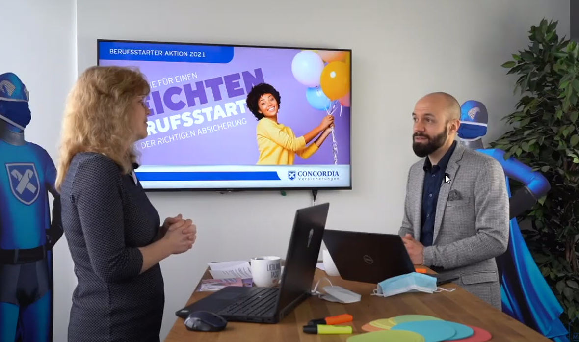 Zwei Concordia Mitarbeiter stehen an einem Tisch und arbeiten am Berufsstarter Konzept 2021.